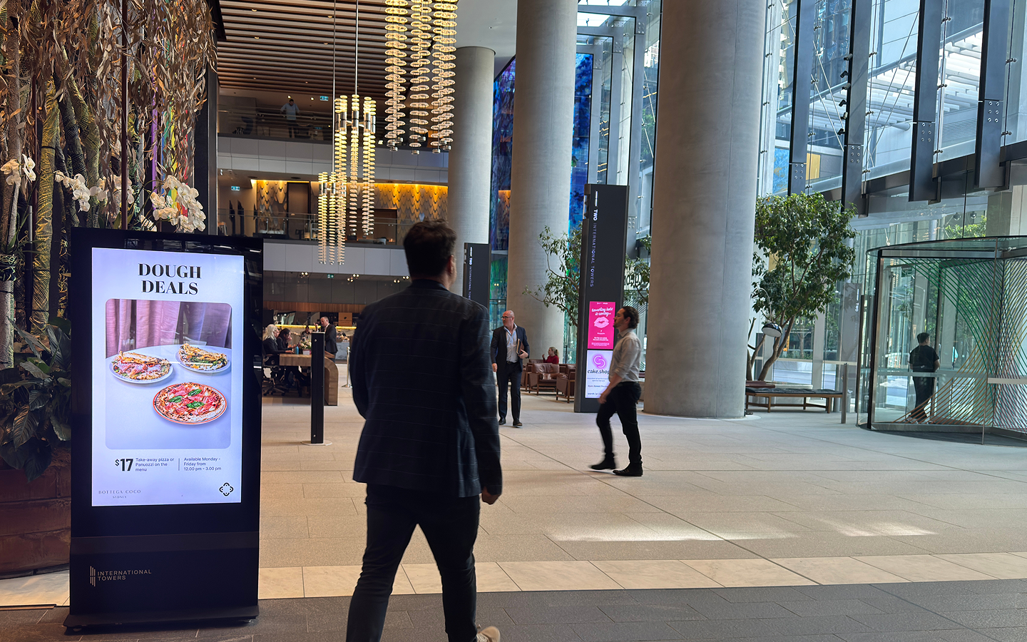 A digital screen in the International Towers lobby advertising a lunch deal, part of the connected precinct experience