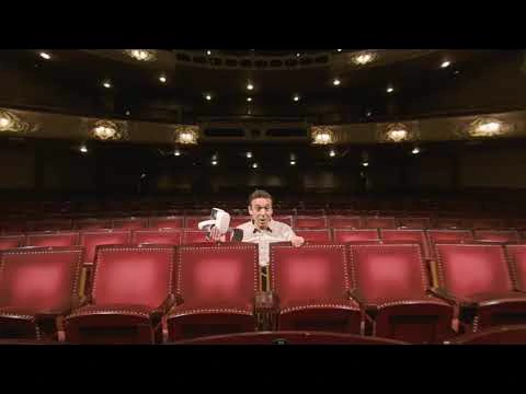 A presenter seated in a theatre auditorium with a VR viewer